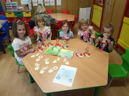 Przedszkolaki kolorują kwiatki dla mamy.