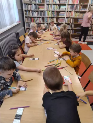 Przedszkolaki kolorują kredkami zakładki do książki.