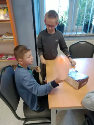 Uczniowie tworzą mikrofon z balona i rolki papieru.