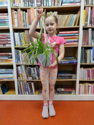 Dziewczynka trzyma w ręce wypleciony kwietnik dla mamy.