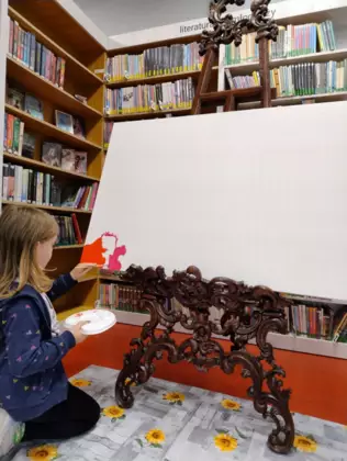 Dzieci na dużej kartce malują farbami obraz.