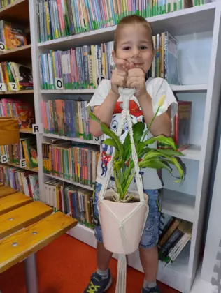 Chłopczyk trzyma w ręce wypleciony kwietnik dla mamy.