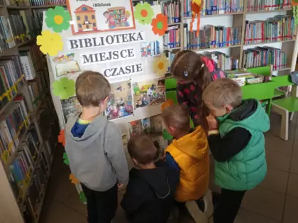 Dzieci oglądają gazetkę biblioteczną.