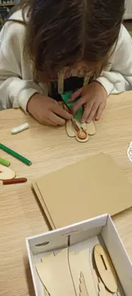 Uczestniczka maluje kredkami anioła dla mamy.