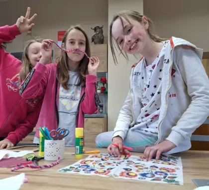 Dziewczyny metodą decoupage oklejają tekturowe ramki na zdjęcia.