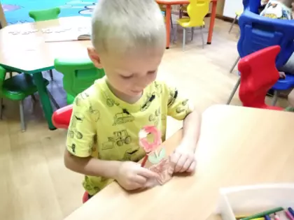 Chłopczyk pokazuje kwiatek pomalowany dla mamy.