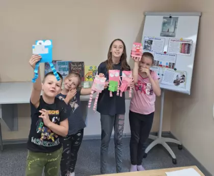 Wspólne zdjęcie dzieci po zajęciach z pracą plastyczną , którą trzymają w rękach.