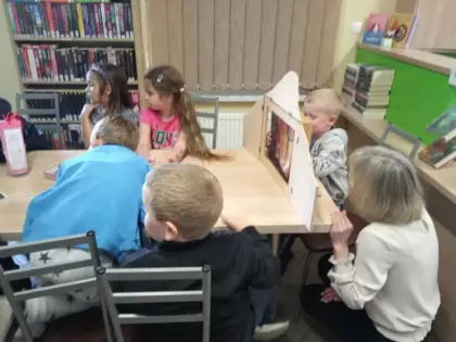 Przedszkolaki słuchają teatrzyku kamishibai.