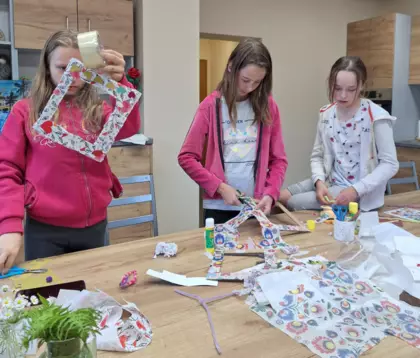 Dziewczyny metodą decoupage oklejają tekturowe ramki na zdjęcia.