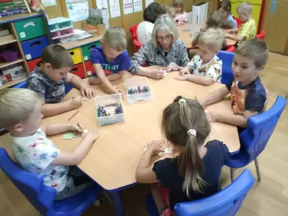 Przedszkolaki kolorują kwiatki dla mamy.