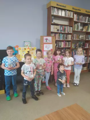 Przedszkolaki trzymają w rękach prezent dla mamy wykonany na zajęciach.