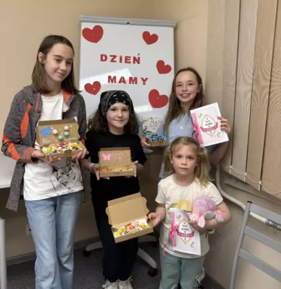 Zdjęcie dzieci po zajęciach. Dziewczyny trzymają w rękach pudełeczka z ciasteczkami i laurki.