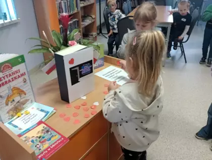 Dziewczynka przykleja serduszko na specjalną książeczkę.