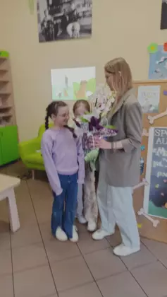 Autorka książek otrzymuje w prezencie kwiat od dzieci.