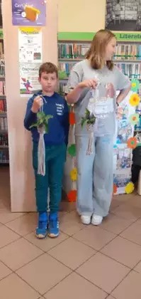 Chłopak  dziewczyna pokazują zrobione kwietniki dla mamy.