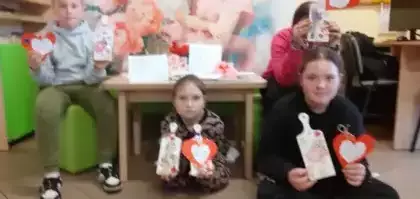 Dwie dziewczynki przedstawiają uroczy upominek dla mamy i kartkę w kształcie serca.
