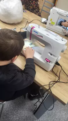Chłopczyk szyje na maszynie.