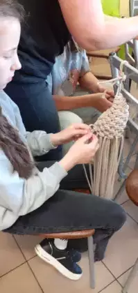 Dziewczyna plączą sznurek tworząc kwietnik.