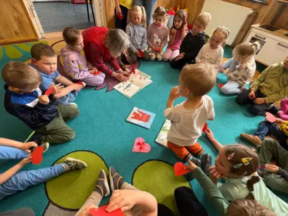 Pani bibliotekarka czyta książkę dzieciom na dywanie