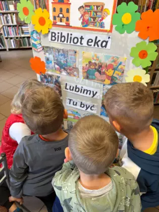 Dzieci oglądają gazetkę biblioteczną.
