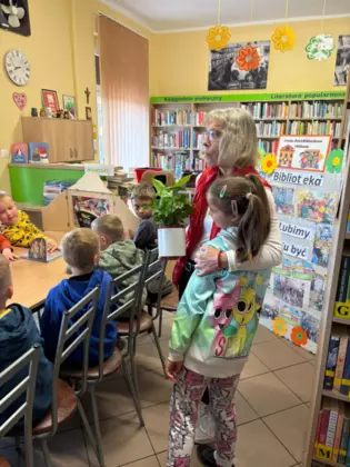 Dziewczynka wręcza kwiatek bibliotekarce.