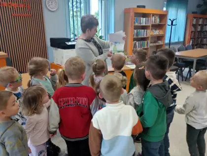 Pani bibliotekarka przregląda razem z dziećmi piękną laurkę, ktorą dostała.