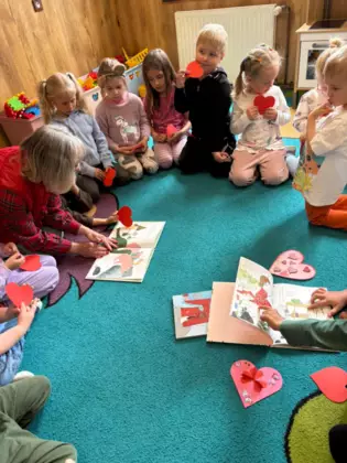 Pani bibliotekarka czyta książkę dzieciom na dywanie.