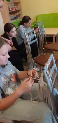 Dziewczyny plączą sznurek tworząc kwietnik.