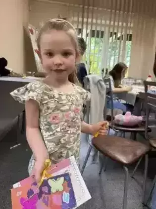 Dziewczynka pokazuje laurkę dla mamy.