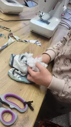 Uczestnik wypełniaczem wypełnia uszyty kształt.