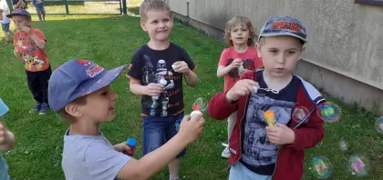 Przedszkolaki na placu zabaw puszczają bańki mydlane.