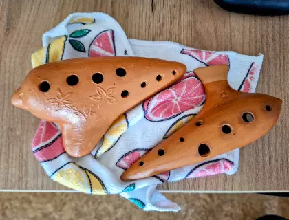 Na kolorowej szmatce leży okaryna mała i okaryna duża.