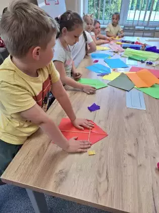 Dzieci na zajęciach plastycznych sklejają latawce.