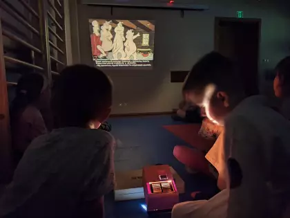 Dzieci oglądają bajki wyświetlane na projektorze.