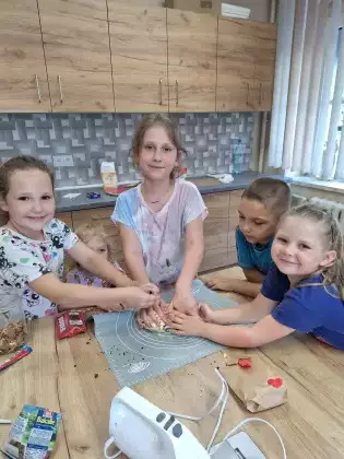 Dzieci wyrabiają ciasto rękami na ciasteczka.