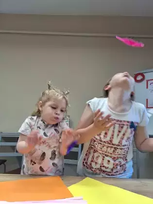 Dziewczynki dmuchają piórko.