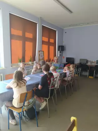Dzieci słuchają opowiadania czytanego przez panią bibliotekarkę.