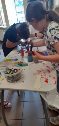 Uczestnicy zajęć wyklejają krawaty kolorowymi guzikami.