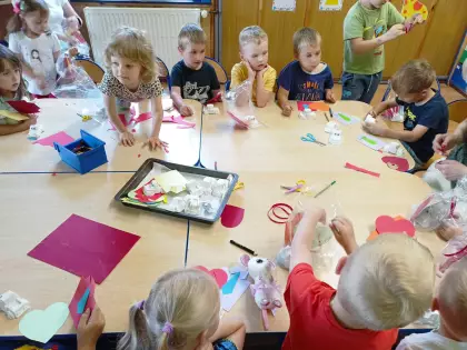 Przedszkolaki siedzą przy wspólnym stole i przygotowują prezenty dla swoich tatusiów.