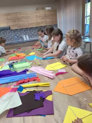 Uczestnicy zajęć tworzą kolorowe latawce.