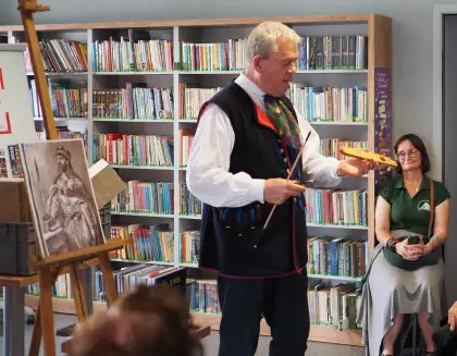 Pan Marek Szołtysek pokazuje starodawny instrument przypominający skrzypce.