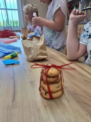 Dziewczynki na zajęciach pakują ciasteczka do przygotowanych torebek.