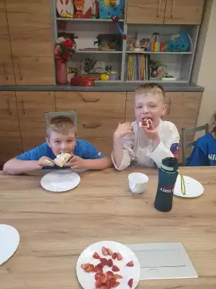 Chłopcy na zajęciach siedzą przy wspólnym stole i jedzą podwieczorek.