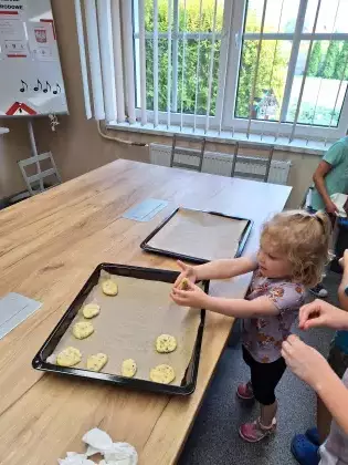 Dziewczynka układa ciasteczka na blaszkę do pieczenia.