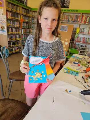 Dziewczyna trzyma w ręce prezent zrobiony dla taty.