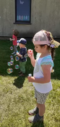 Przedszkolaki na placu zabaw puszczają bańki mydlane.