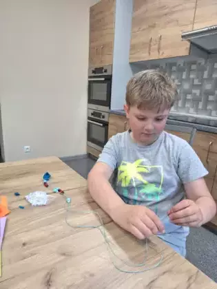 Chłopczyk robi korale dla mamy.