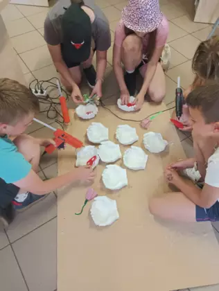 Dzieci oklejają gipsowe serduszka dla taty.