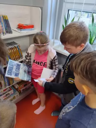 Dzieci oglądają książeczki w bibliotece.