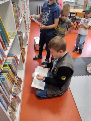 Dzieci oglądają książeczki w bibliotece.